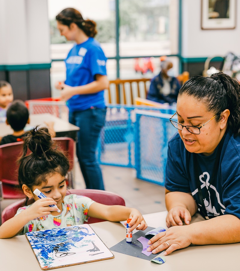 Caregiver helping a young girl with an art project during RCSA’s Developmental Childcare Program